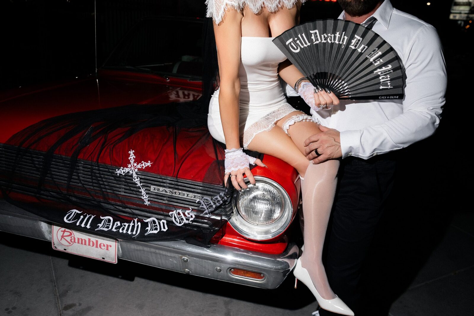 Close up shot of a bride and groom posing with a classic car.
