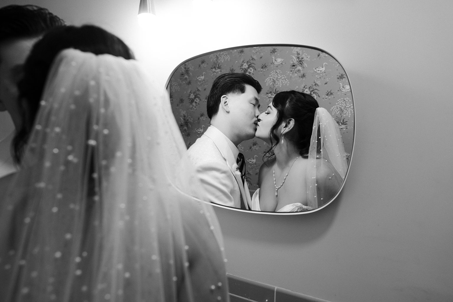 Black and white photo of a bride and groom kissing in the bathroom at Sure Thing Chapel in Las Vegas