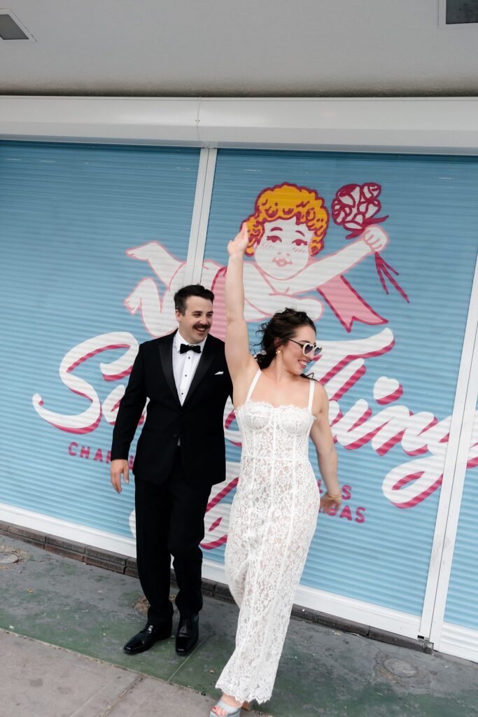 Bride and groom posing in front of an outdoor Sure Thing Chapel sign.