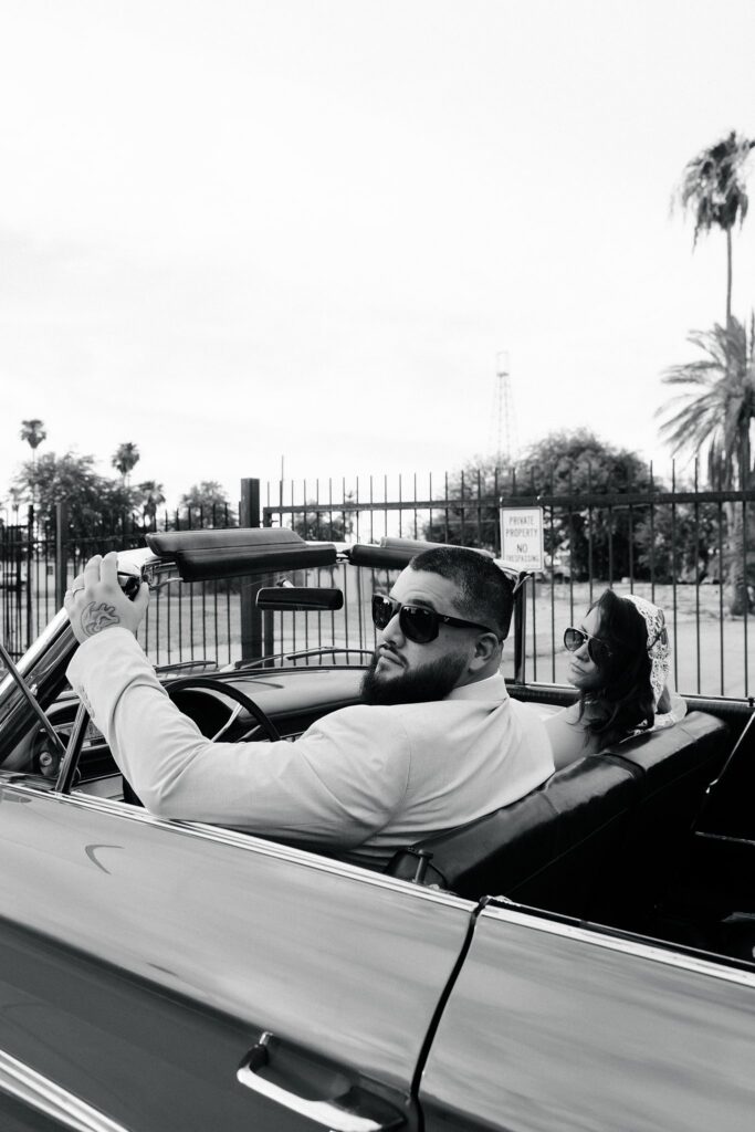 Black and white photo of a couple posing in the classic car at Sure Thing Chapel in Las Vegas.
