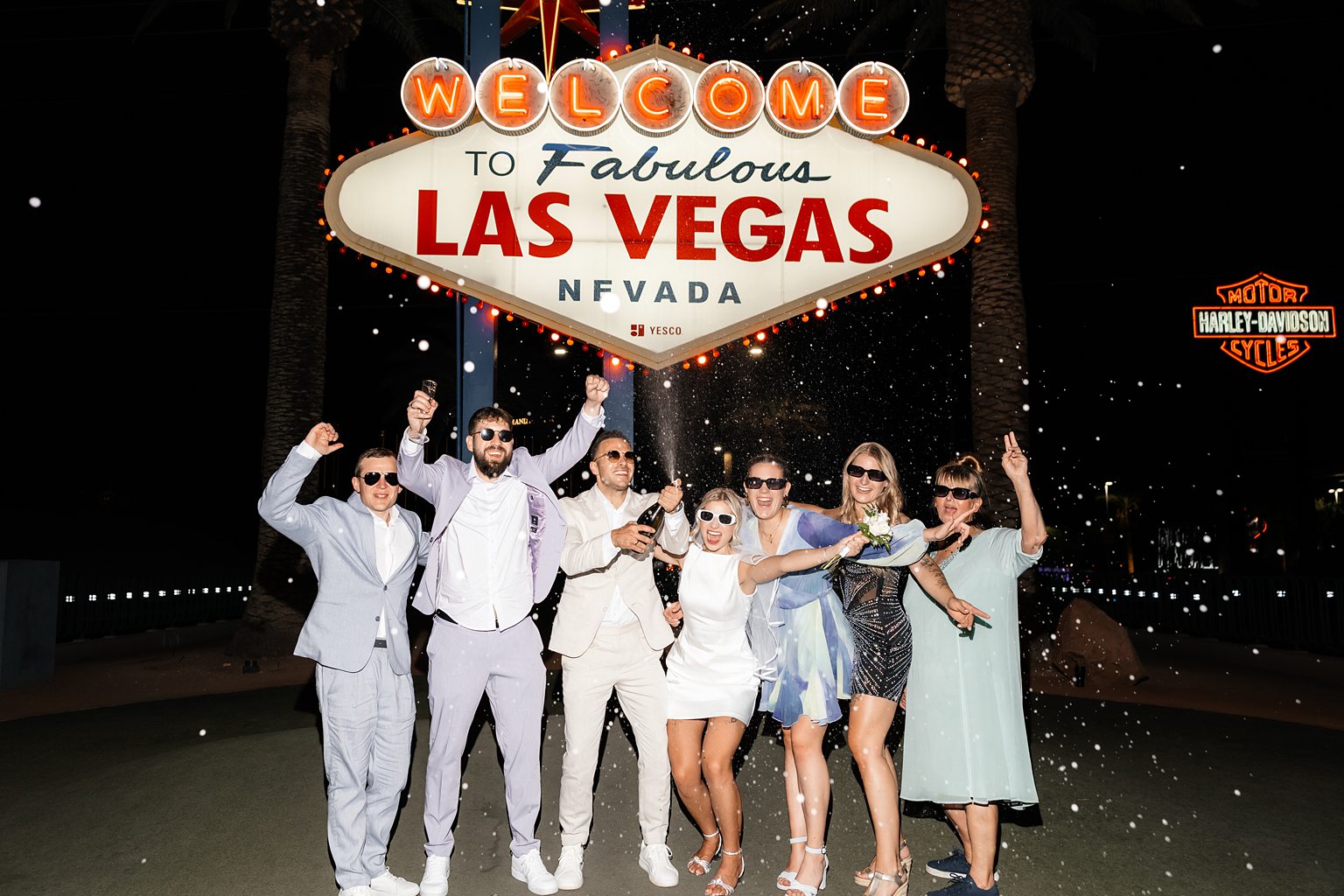 Bride, groom, and their friends popping champagne 5 Mistakes to Avoid When Eloping in Vegas