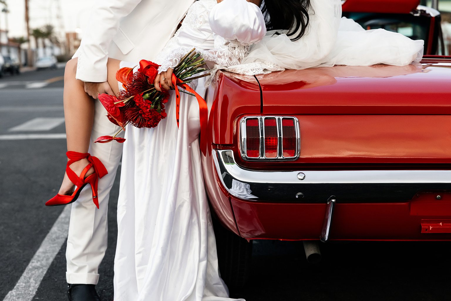 Couple posing with a red car for their Las Vegas elopement