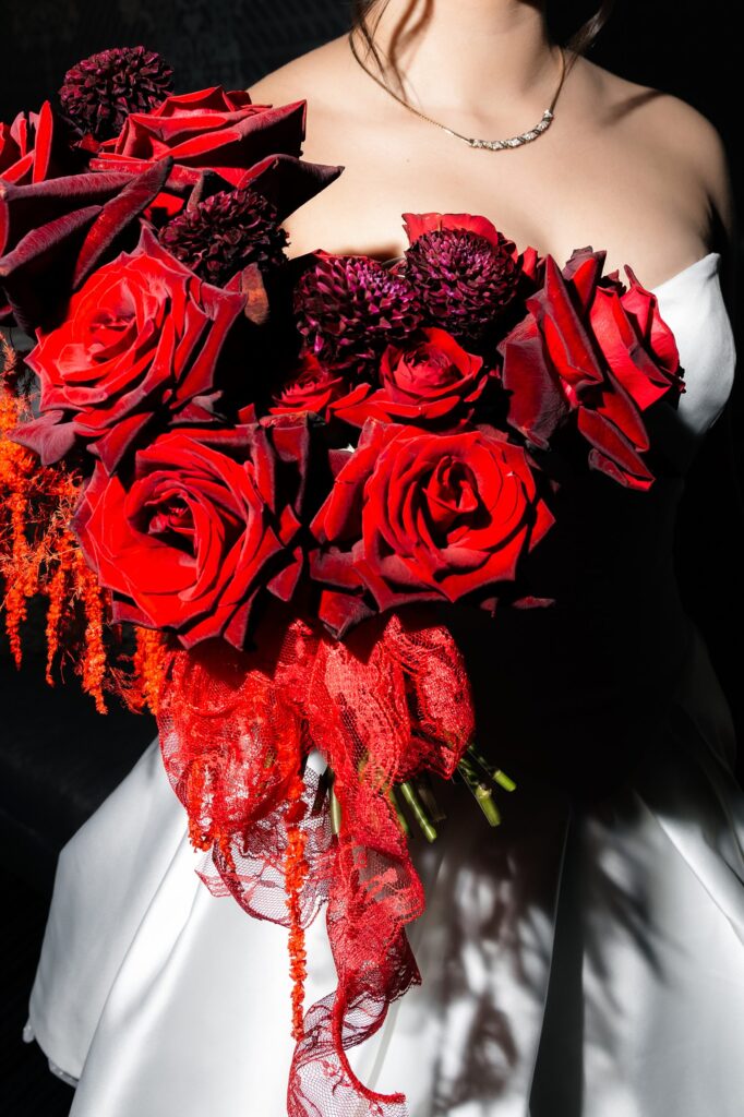 Bride holding a bright red bouquet made by Night Garden Floral