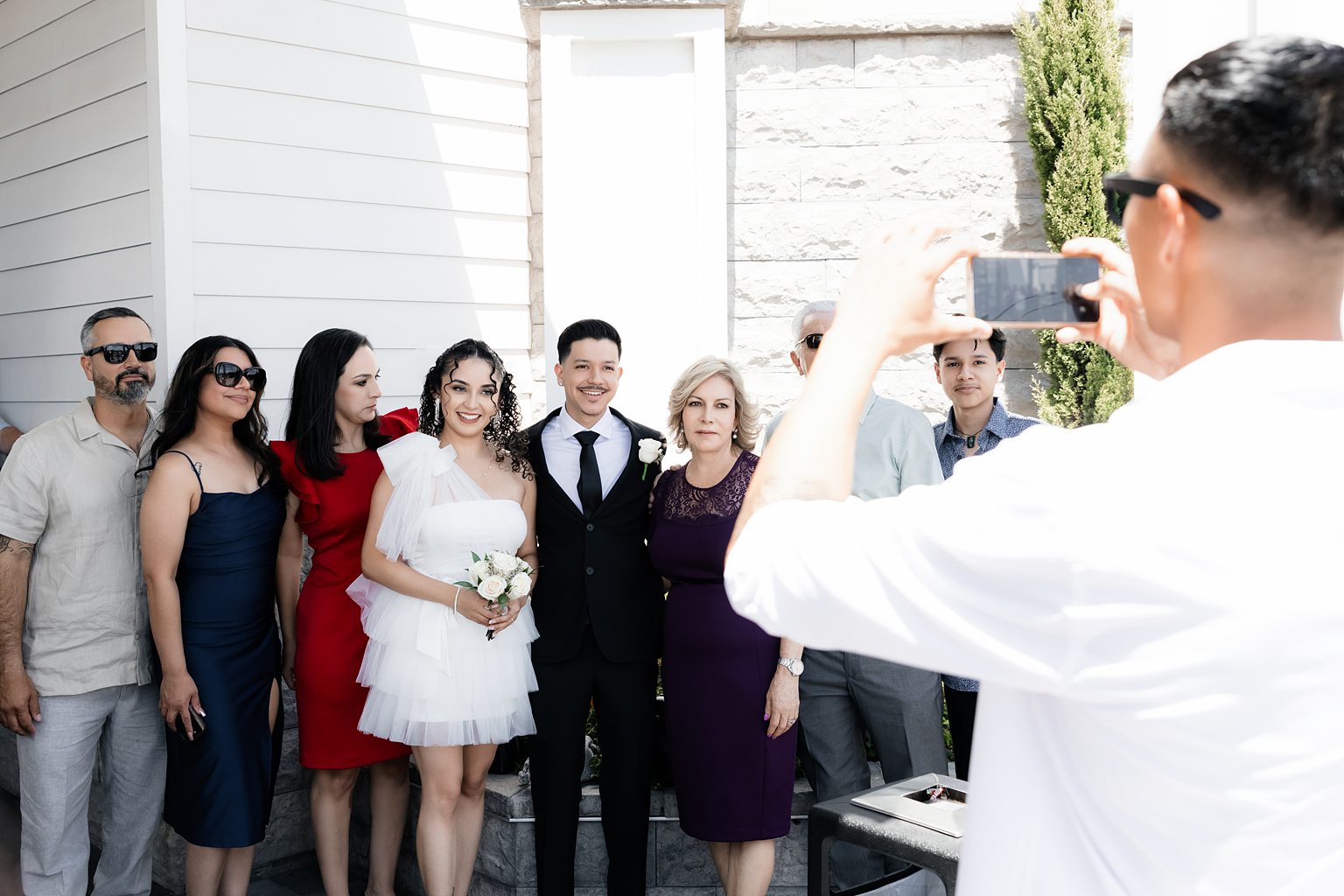 Bride and groom taking photos outside with family