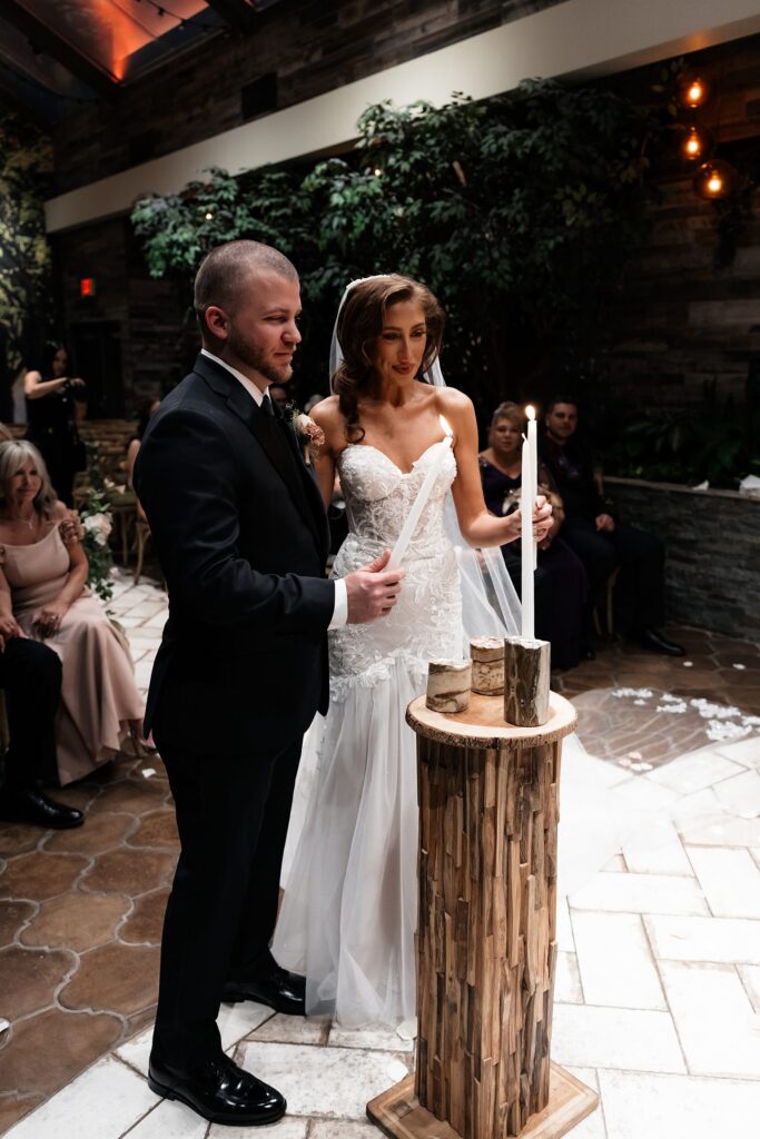 Bride and groom performing a unity candle ceremony during their Chapel of Flowers wedding ceremony in The Glass Gardens