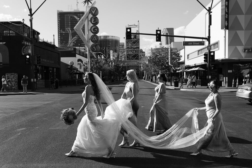 Black and white photo of a bride and her bridesmaids walking on Fremont Street