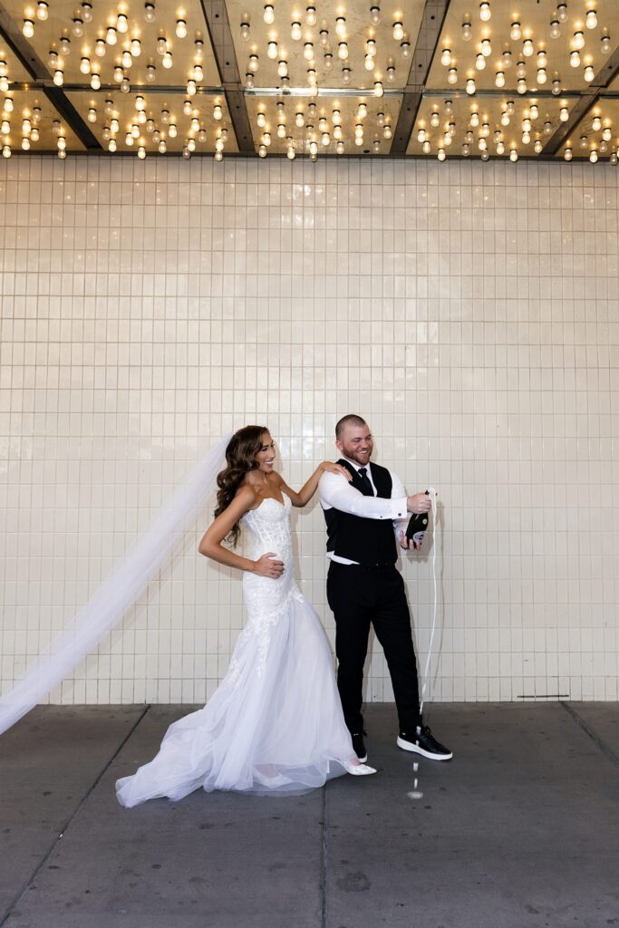 Bride and groom popping champagne under the Plaza lights