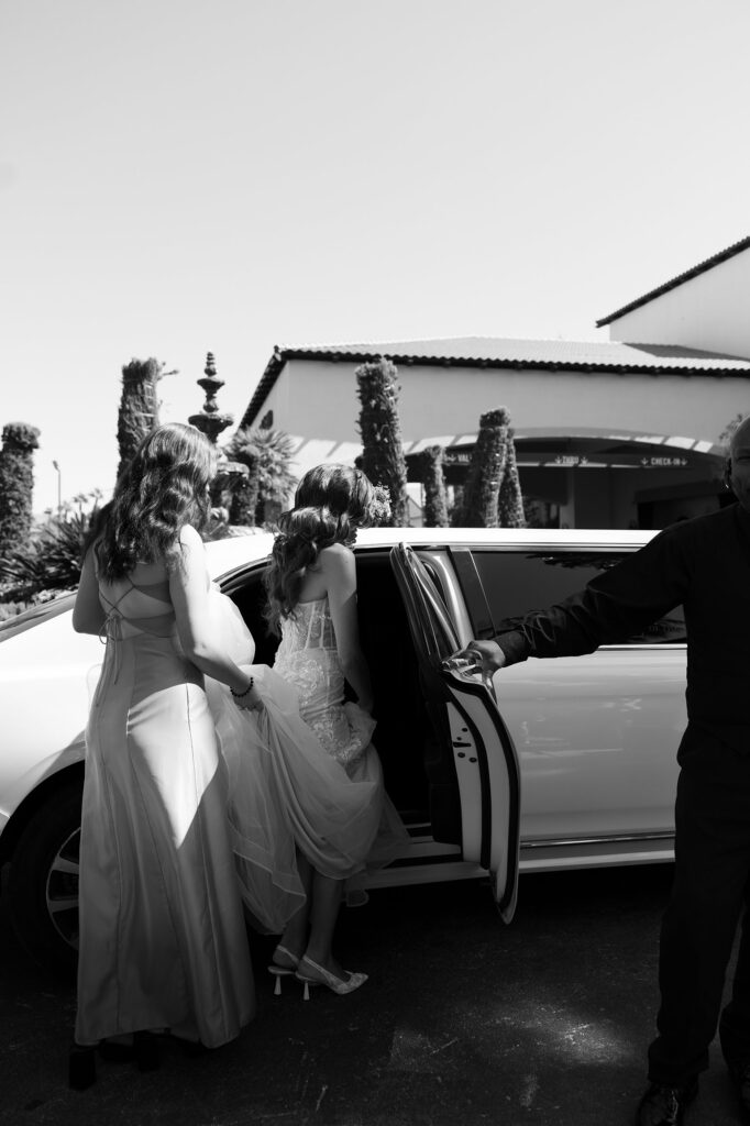 Black and white photo of a bride getting into a limo