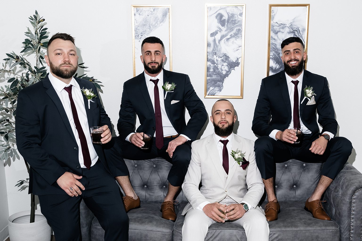 Groom and his three groomsmen posing for photos as they drink whiskey before the ceremony