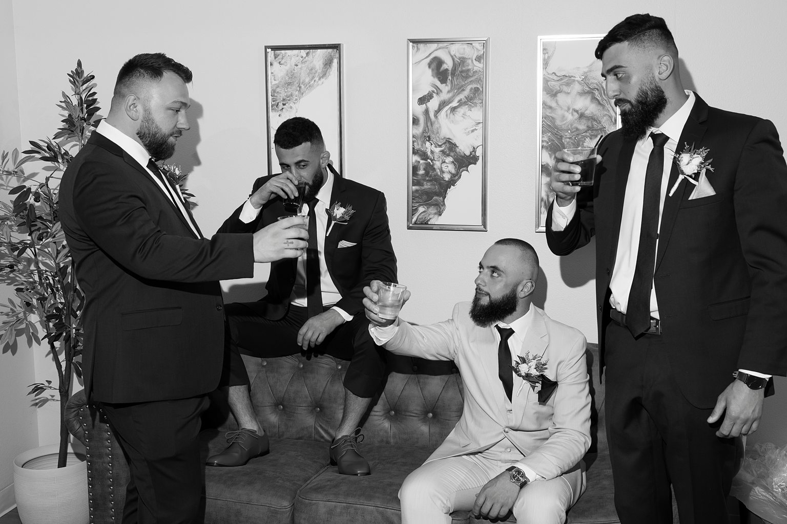 Groom and his three groomsmen posing for photos as they drink whiskey before the ceremony