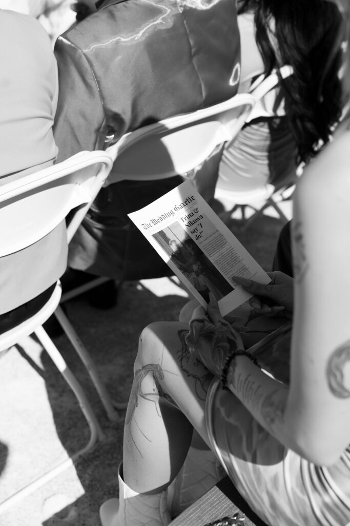 Black and white photo of a guest looking at the wedding newspaper 