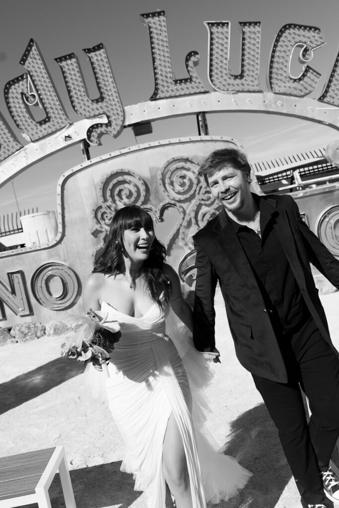 Black and white photo of a bride and groom walking down the aisle for their Neon Museum wedding photos