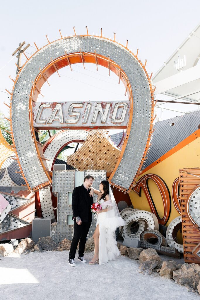 Bride and groom posing in front of a casino sign for their Las Vegas wedding photos