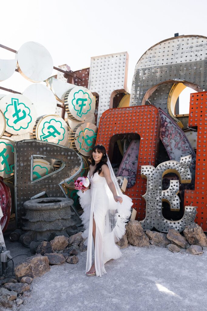 Bride posing for her Neon Museum wedding photos wearing a BHLDN Watters Lupine Wedding Dress