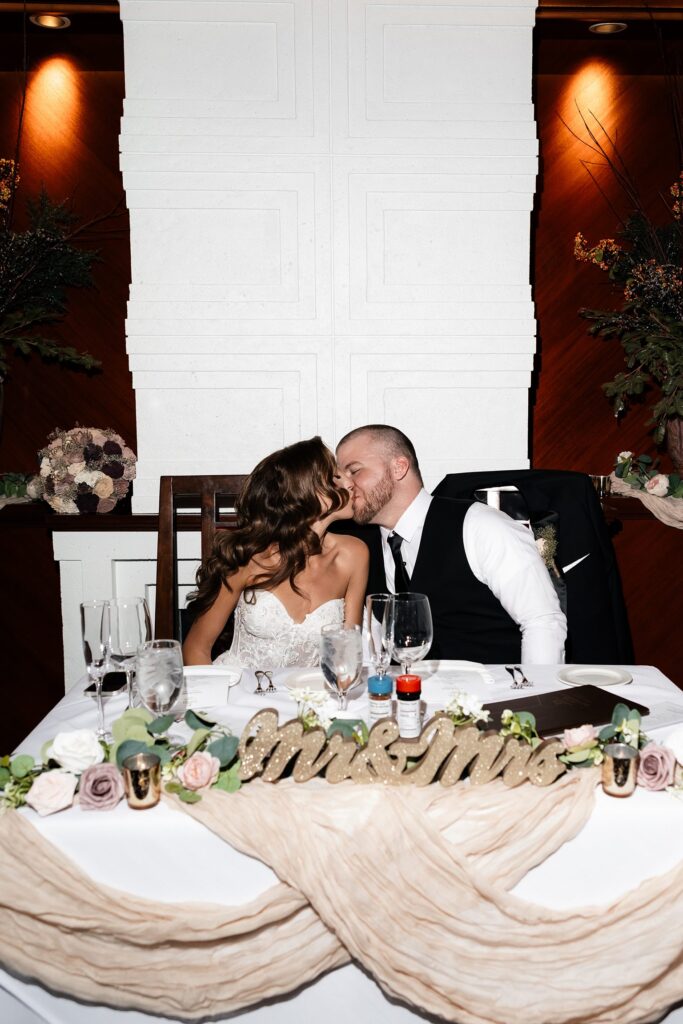 Bride and groom kissing at the sweethearts table