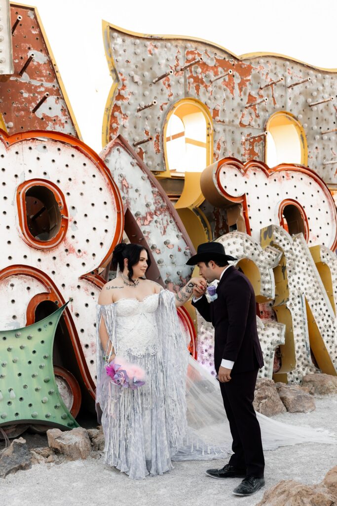 Groom kissing his brides hand during their Neon Museum wedding photos