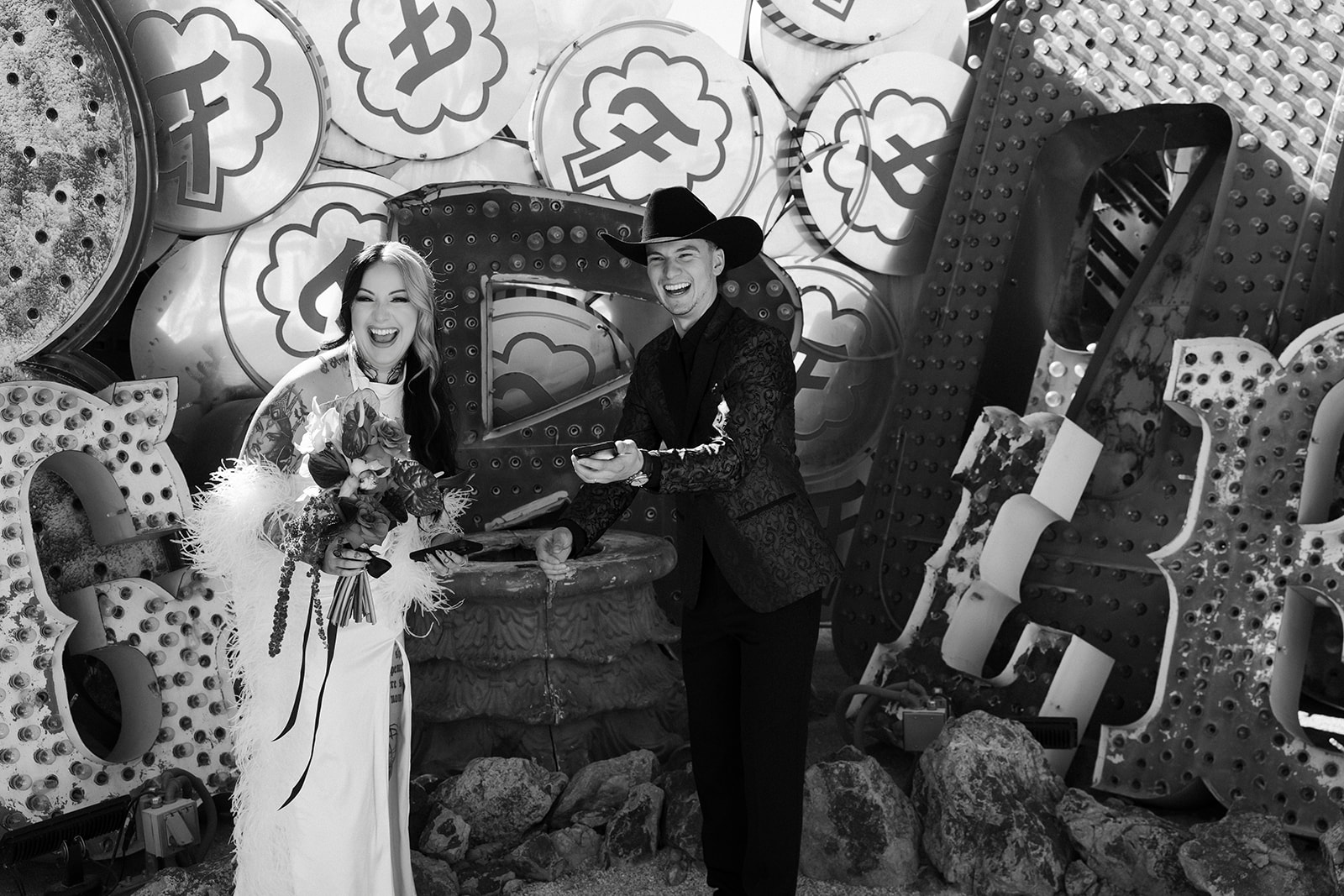 Candid black and white photo of a bride and groom laughing in The Neon Museum.
