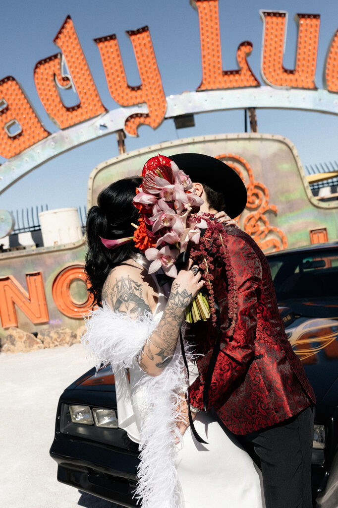Bride and groom kissing behind the brides bouquet during their Neon Museum wedding photos.