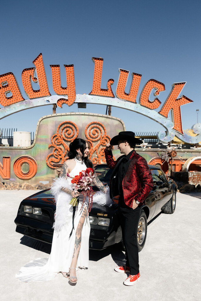 Bride and groom posing with a vintage black car in the Neon Museum.
