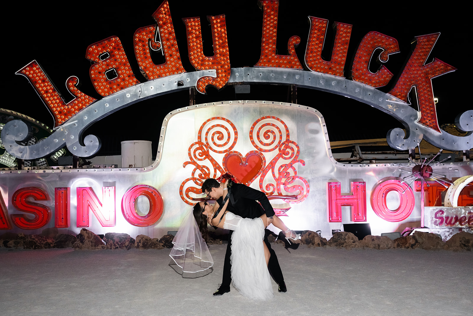 Bride and groom posing in front of the Lady Luck sign for their Neon Museum wedding photos at night.