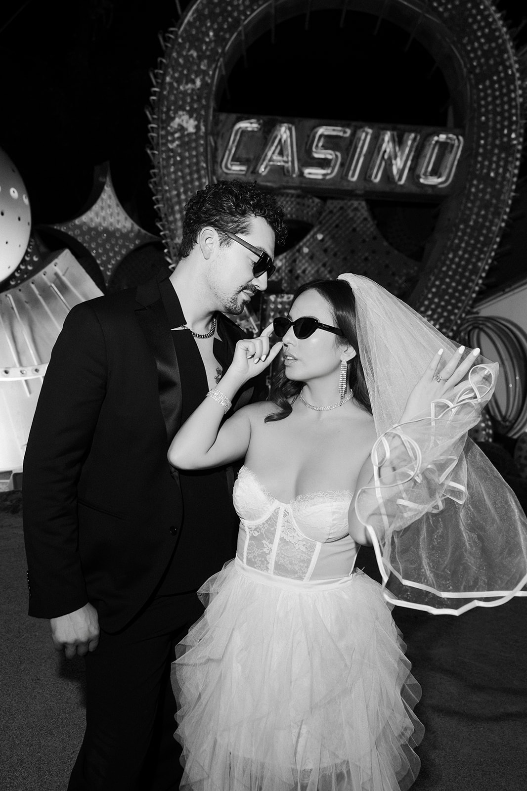 Editorial black and white portraits of bride and groom posing in The Neon Museum at night.
