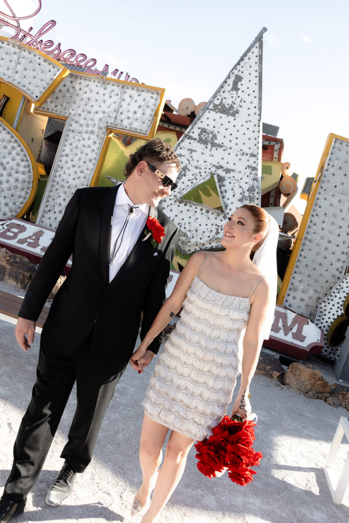 Bride and groom walking through the Neon Museum during golden hour.