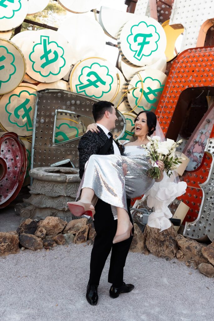 Groom lifting up his bride during their Neon Museum wedding portraits in Las Vegas