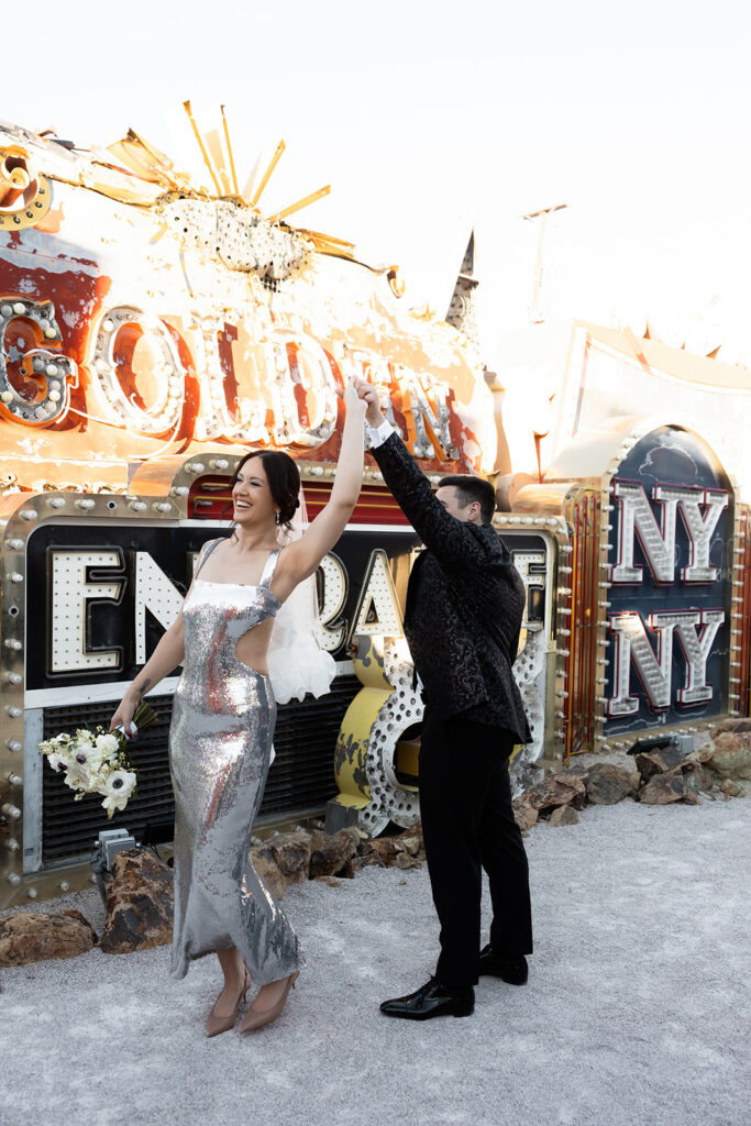 Bride and groom dancing in The Neon Museum during golden hour.