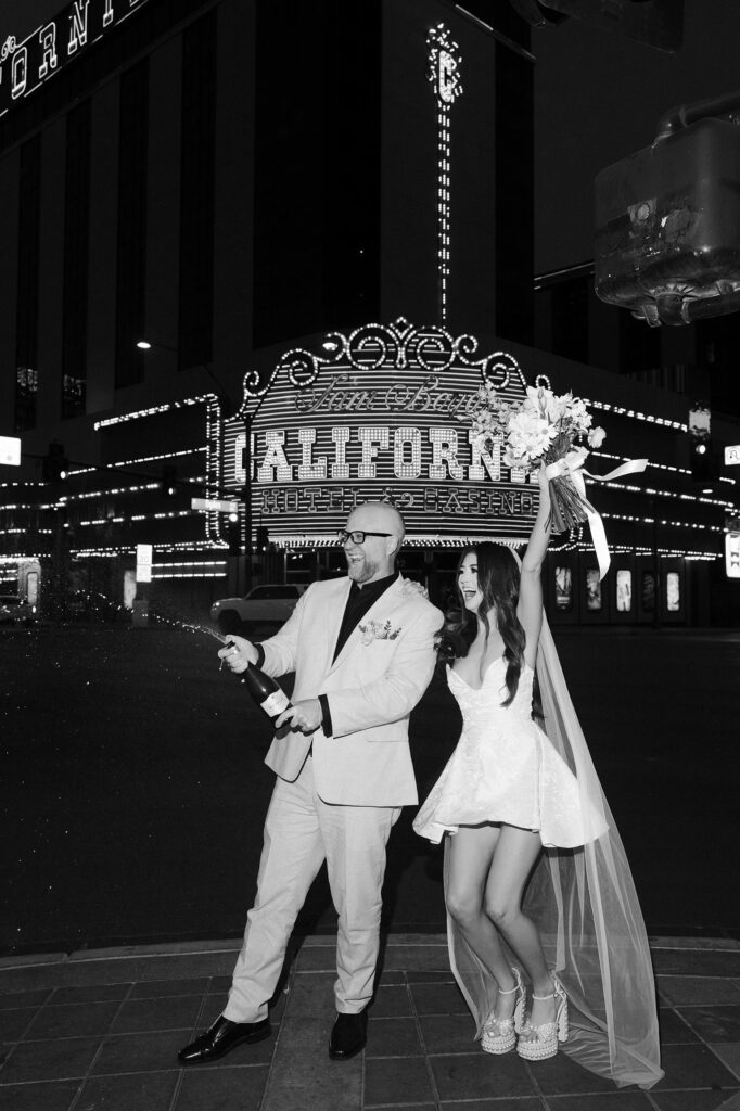 Bride and groom popping champagne on Fremont Street after their Las Vegas elopement