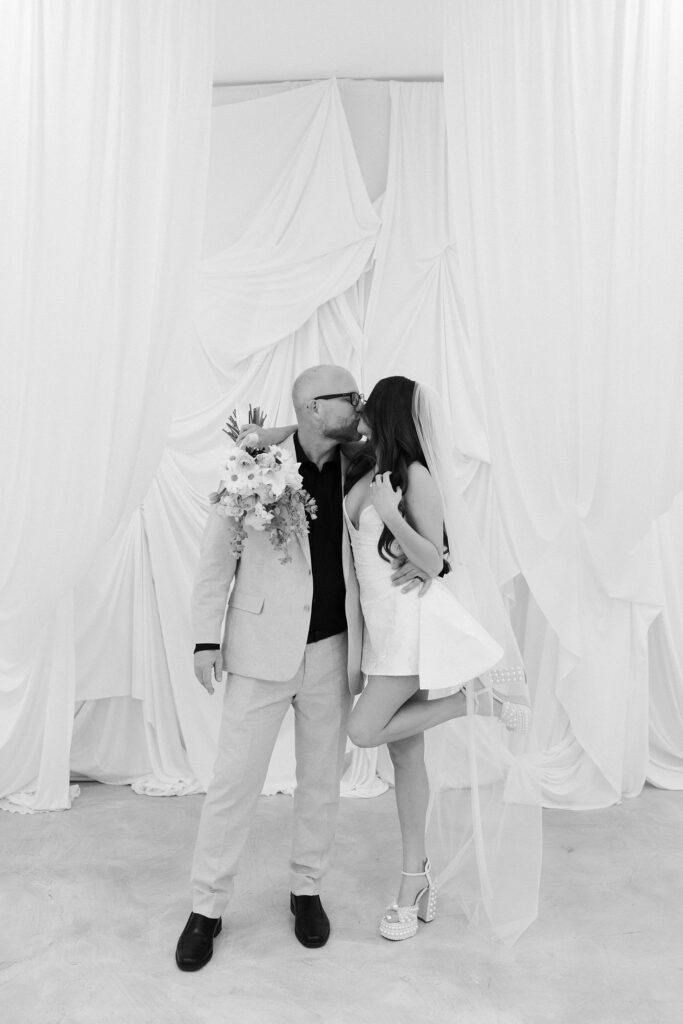Black and white photo of a bride and groom kissing