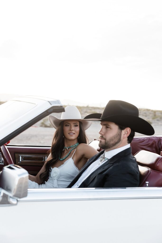 Couple sitting in a convertible during their editorial engagement photos in Las Vegas with desert views behind them.