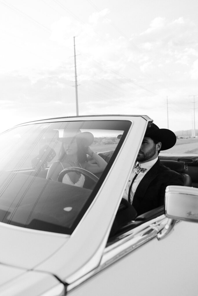 Editorial black and white shot of a couple inside a classic convertible during their desert engagement session in Las Vegas.