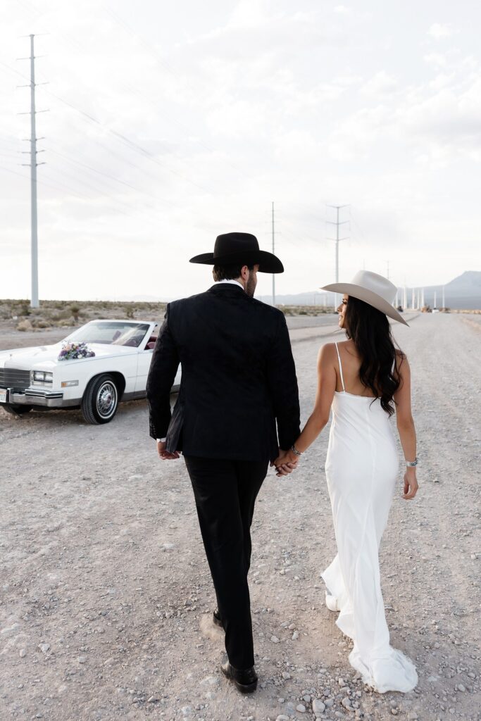 Engaged couple walking hand in hand during their desert engagement photos in Las Vegas, wearing modern western attire.