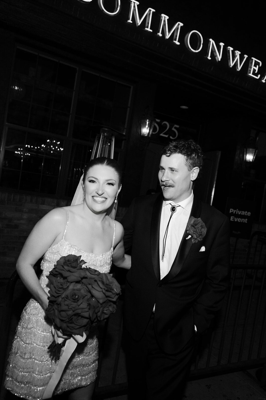 Black and white photo of a bride and groom posing in front of Commonwealth in Las Vegas