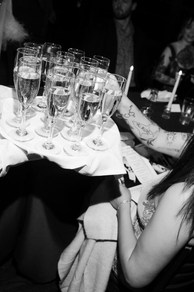 Black and white photo of champagne being passed during a Las Vegas wedding reception at Carmines Italian Restaurant.