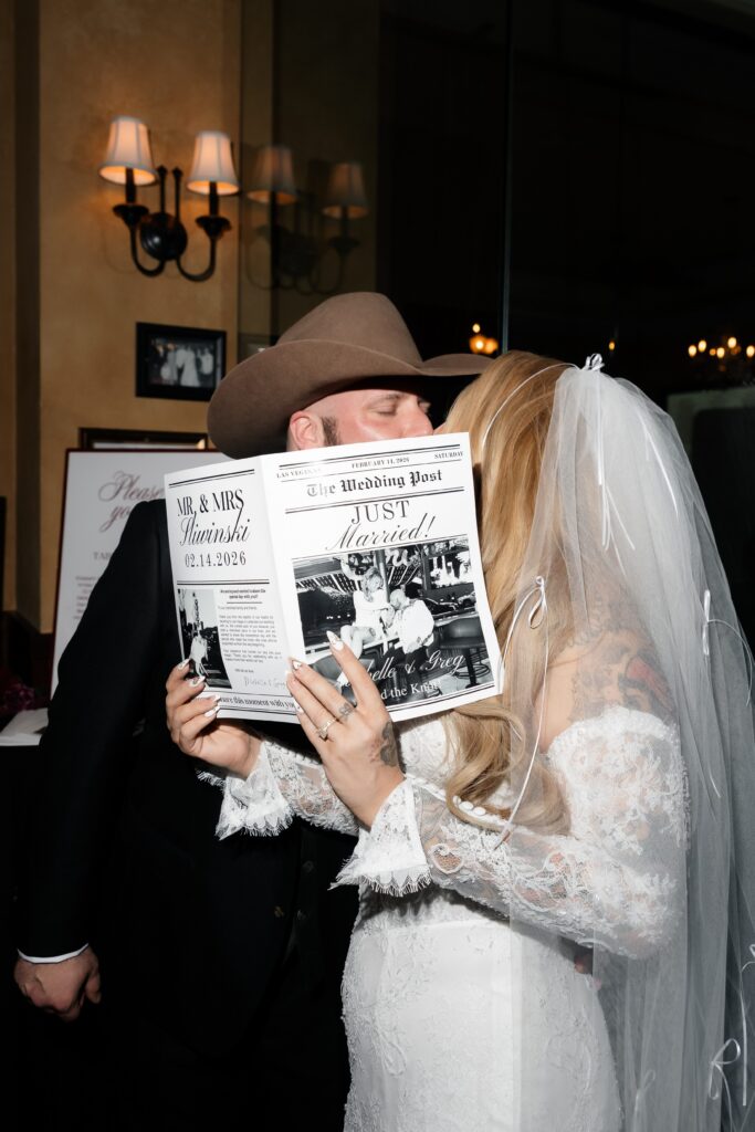 Bride and groom kissing behind their just married wedding newspaper during their reception at Carmines Italian Restaurant in Las Vegas.
