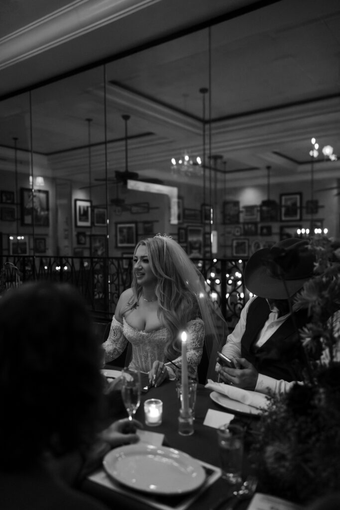 Black and white photo of a bride and groom having dinner during their reception at Carmines Italian Restaurant in Las Vegas.