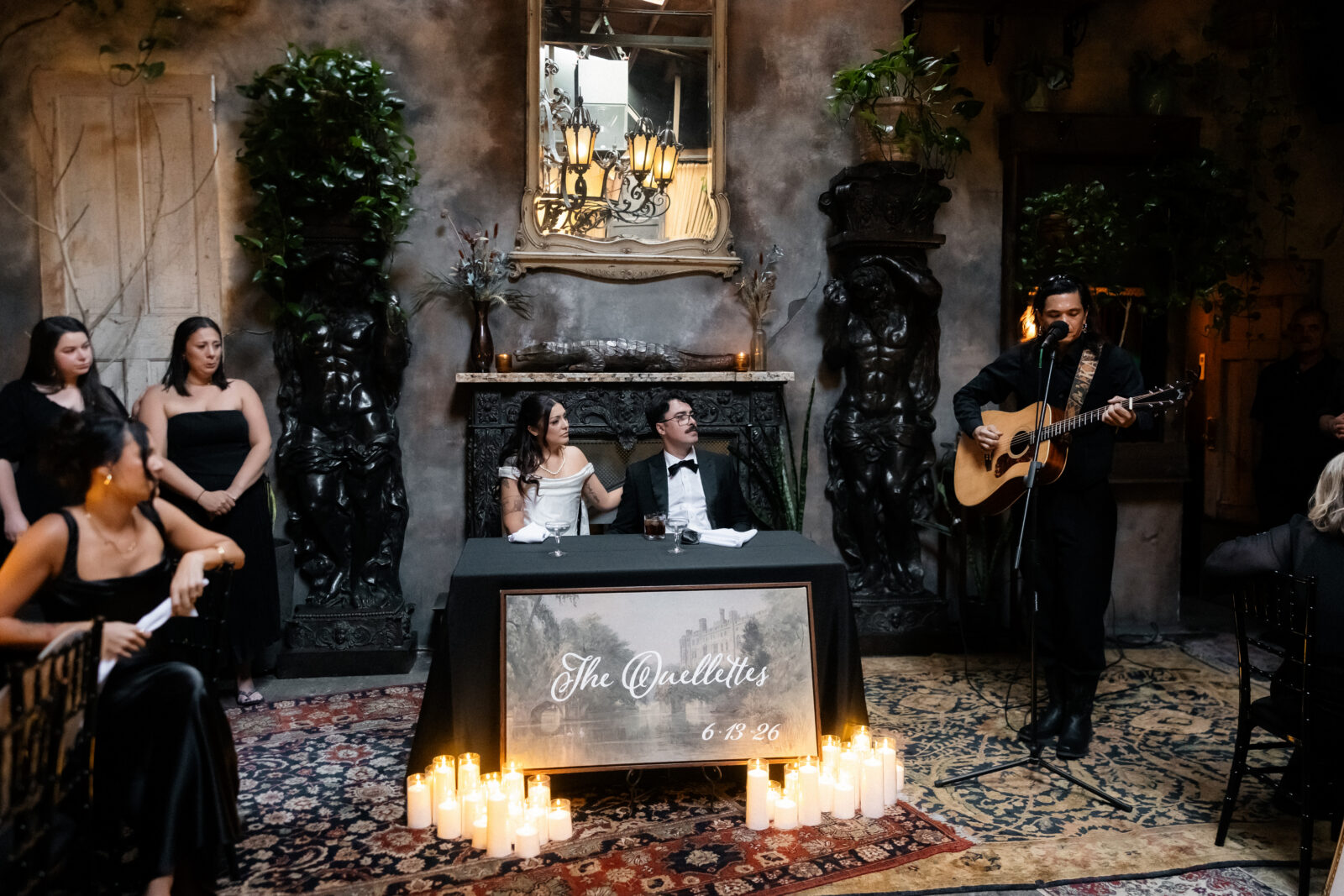 Bride and groom seated at their Doberman Drawing Room wedding reception with a live musician.