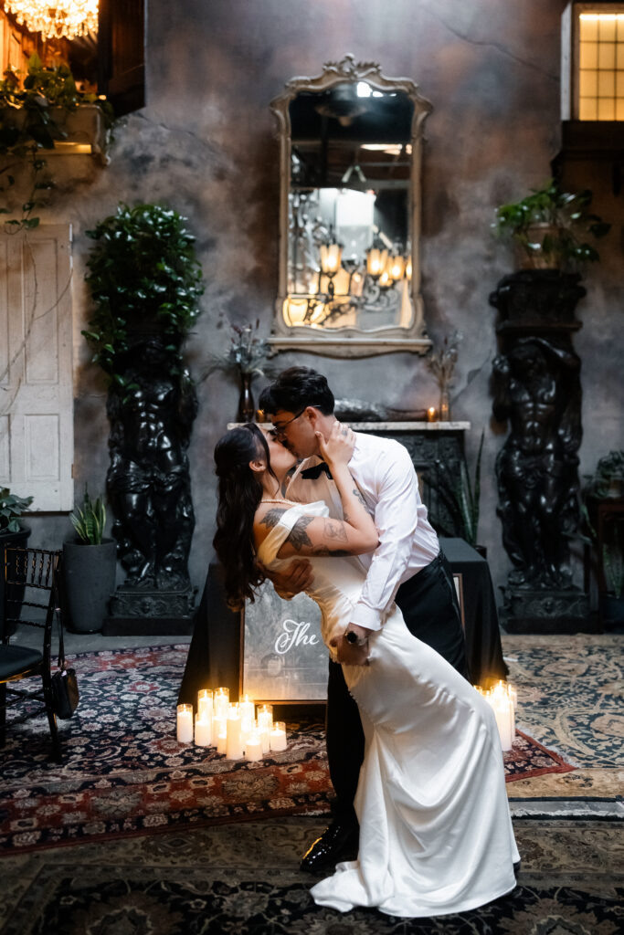 Bride and groom kissing in front of candlelit decor at Doberman Drawing Room in Las Vegas.