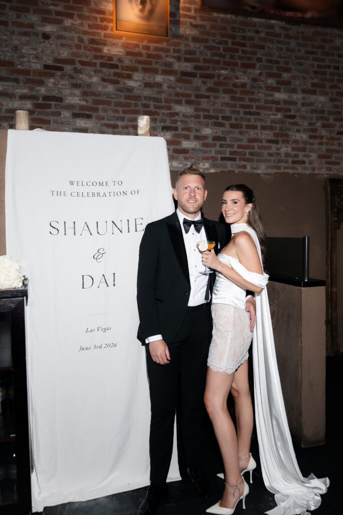 Bride and groom posing beside their wedding welcome sign at TAO Asian Bistro in Las Vegas.