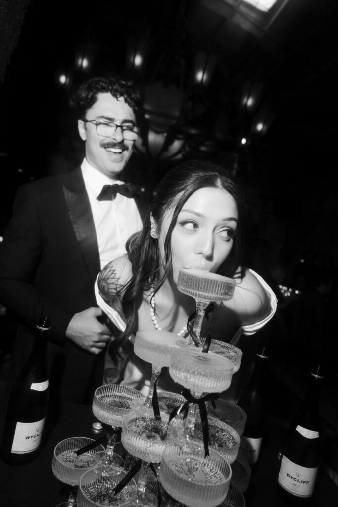 Bride sipping from a champagne tower during a Las Vegas wedding reception.