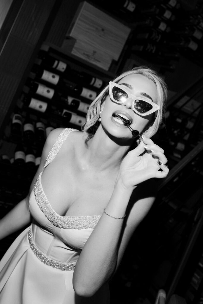 Bride posing in sunglasses with a cherry during her Las Vegas wedding reception.