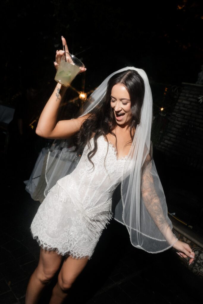 Bride holding a cocktail up in the air.