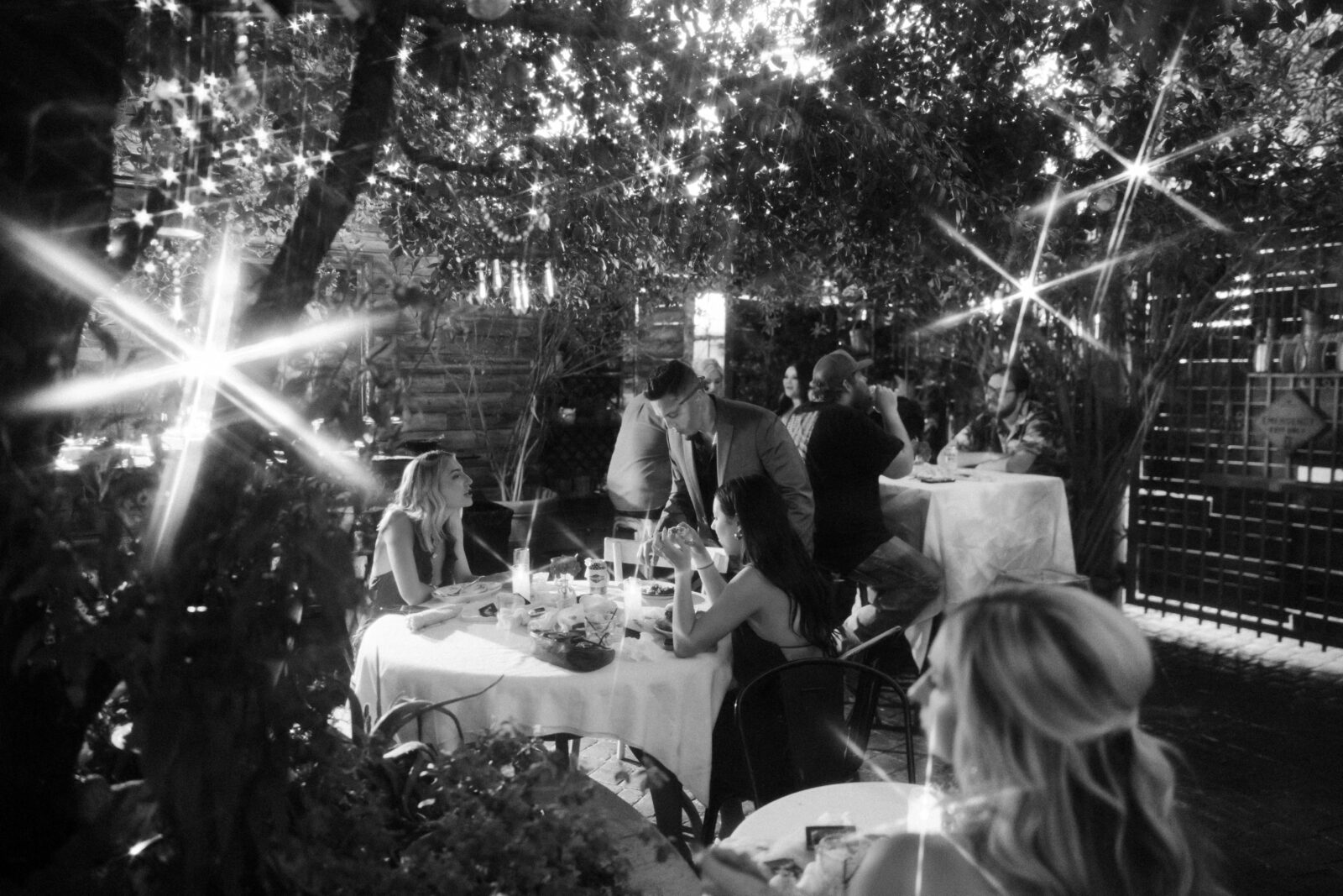 Candid black and white photo of guests eating dinner and mingling during a Las Vegas micro wedding reception at The Park on Fremont.
