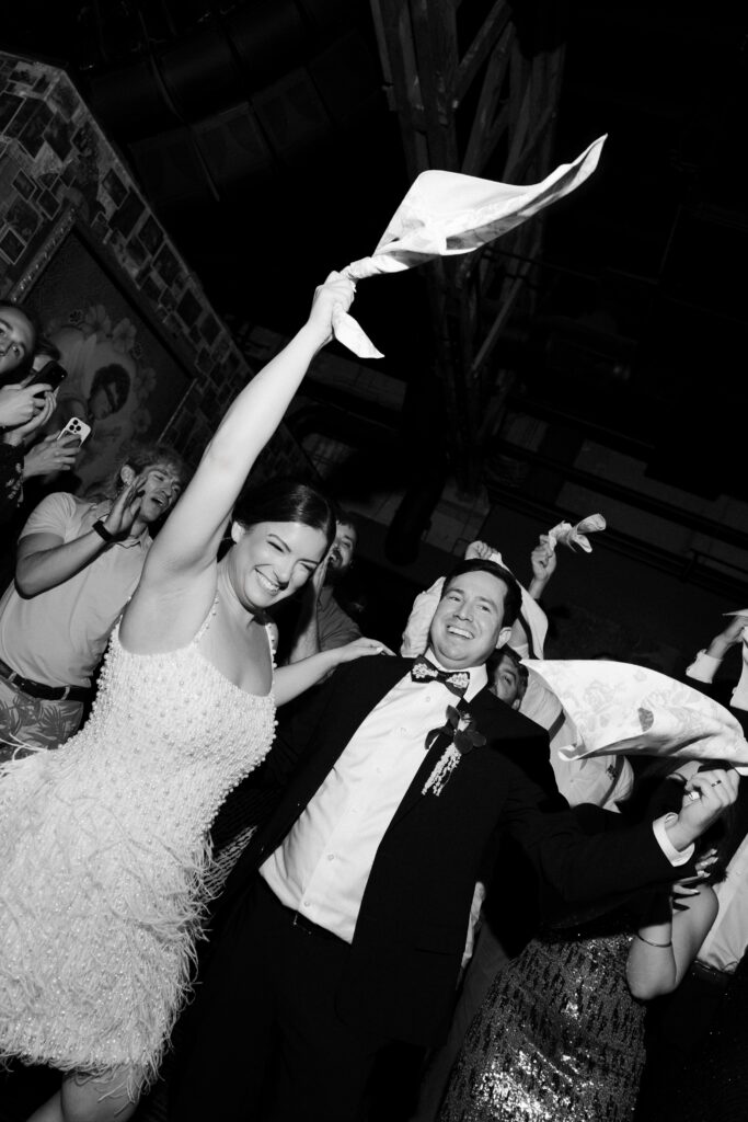 Black and white photo of a bride and groom waving towels during their Las Vegas wedding reception at Commonwealth.