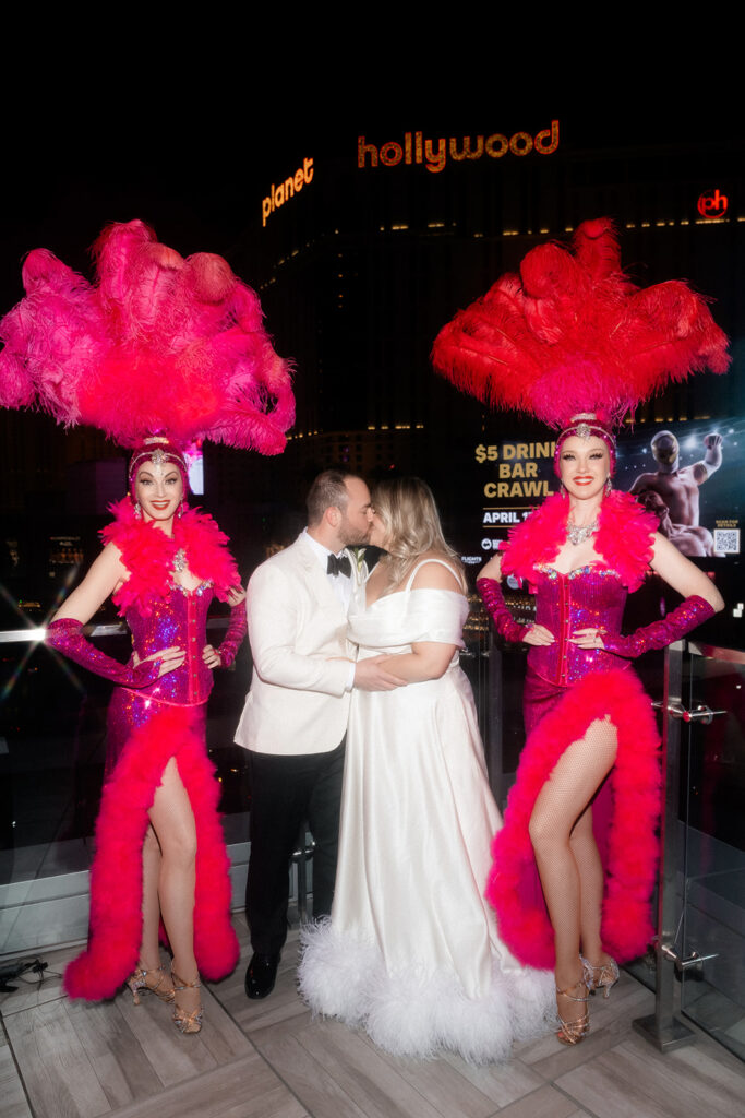 Bride and groom kissing next to show girls during their Ocean Prime Las Vegas wedding reception.