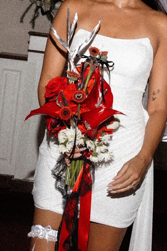 Close up shot of the bride holding a red bouquet by Night Floral Garden