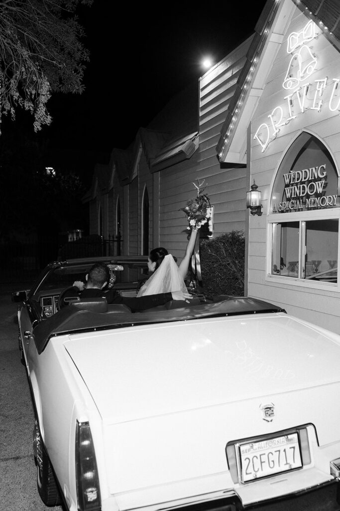 Robin Thicke and April Love Geary posing inside a classic car in front of A Special Memory Wedding Chapel