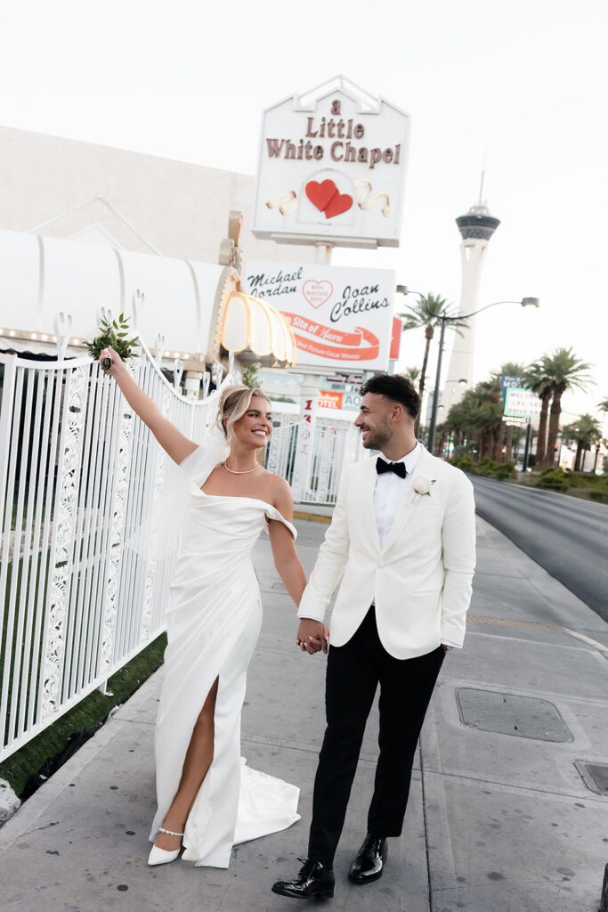 Bride and groom walking hand in hand down the sidewalk outside of a Little White Chapel in Las Vegas.