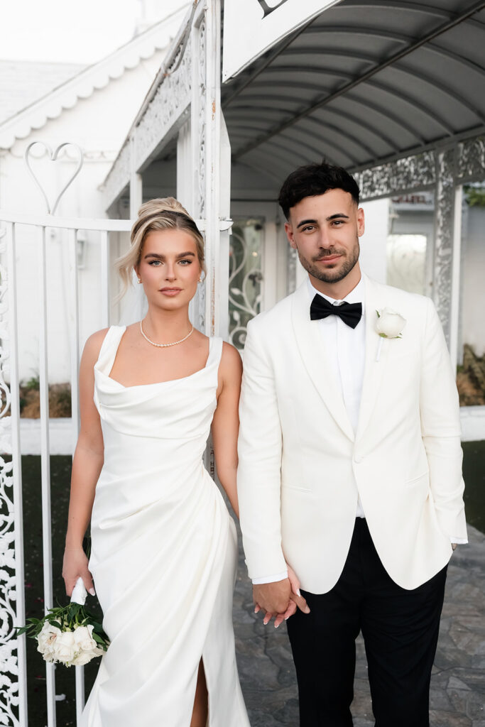 Close up shot of a bride and groom holding hands outside of The Little White Wedding Chapel for their classy elopement in Vegas.